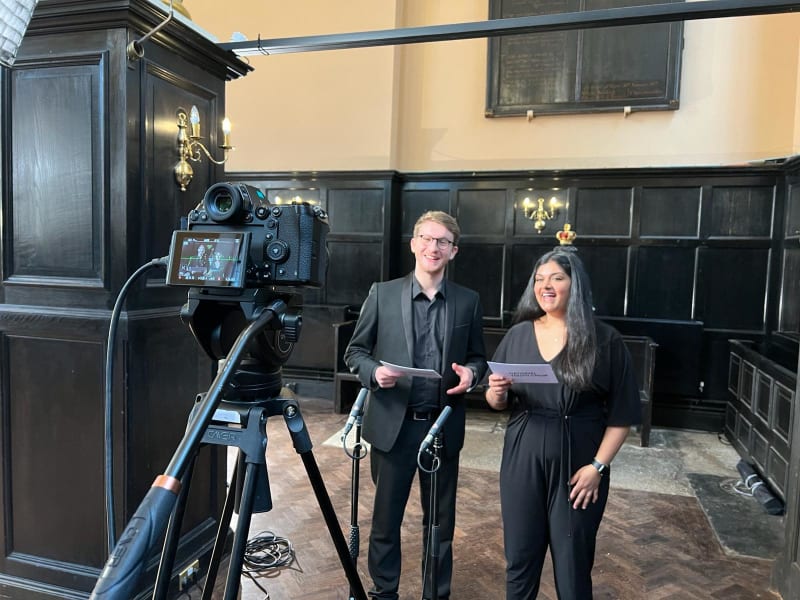 Chris and Sarina, a south asian woman, presenting to camera holding cue cards